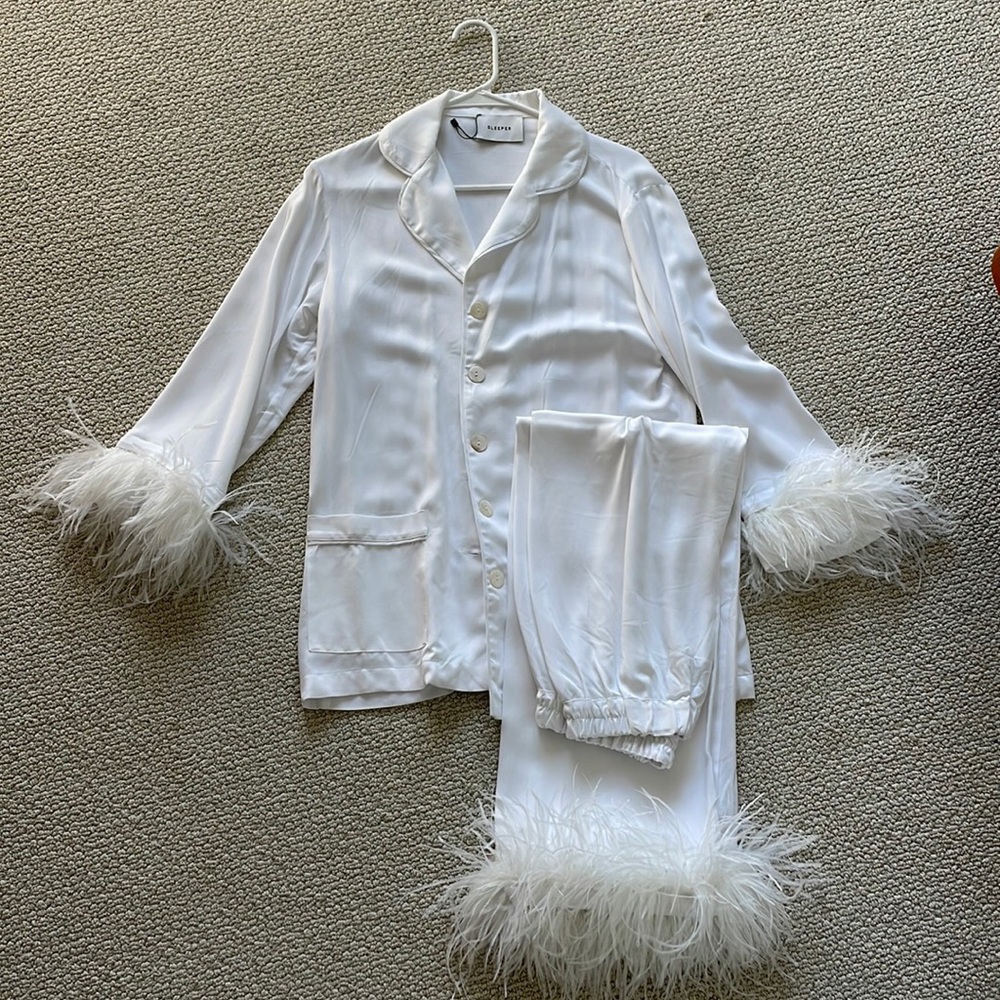 Sleeper party pajamas in white with feather trim on the top and bottom.